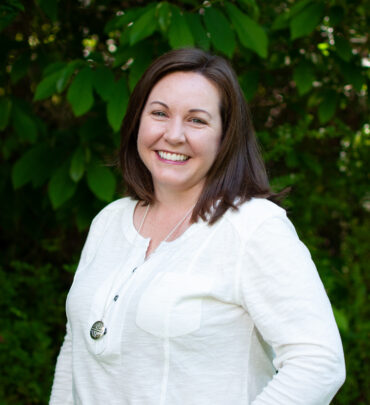 A woman standing in front of some trees