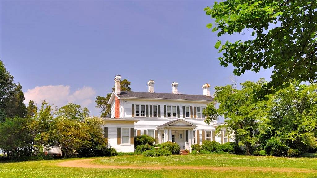 A large white house sitting in the middle of a field.