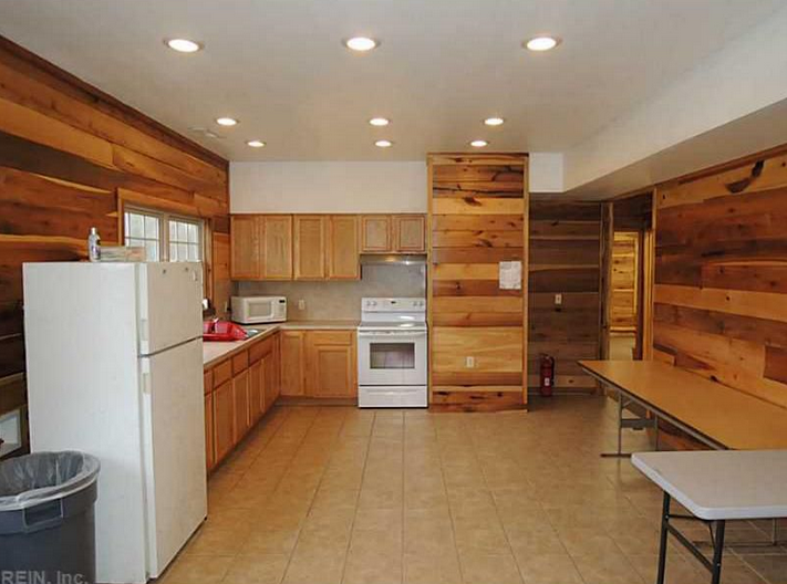 A kitchen with wooden walls and white appliances.