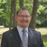 A man in a suit and tie standing outside.