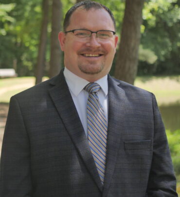 A man in a suit and tie standing outside.