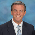 A man in suit and tie smiling for the camera.