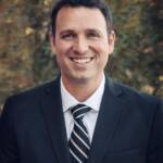 A man in a suit and tie smiling for the camera.