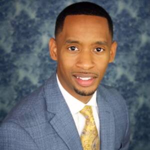 A man in a suit and tie standing up against a wall.