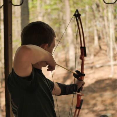 A man is holding his bow and aiming at the target.