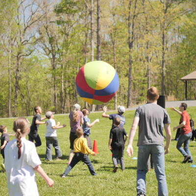 A group of people in the grass with a kite.