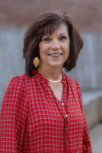 Smiling woman in a red checkered shirt outdoors.